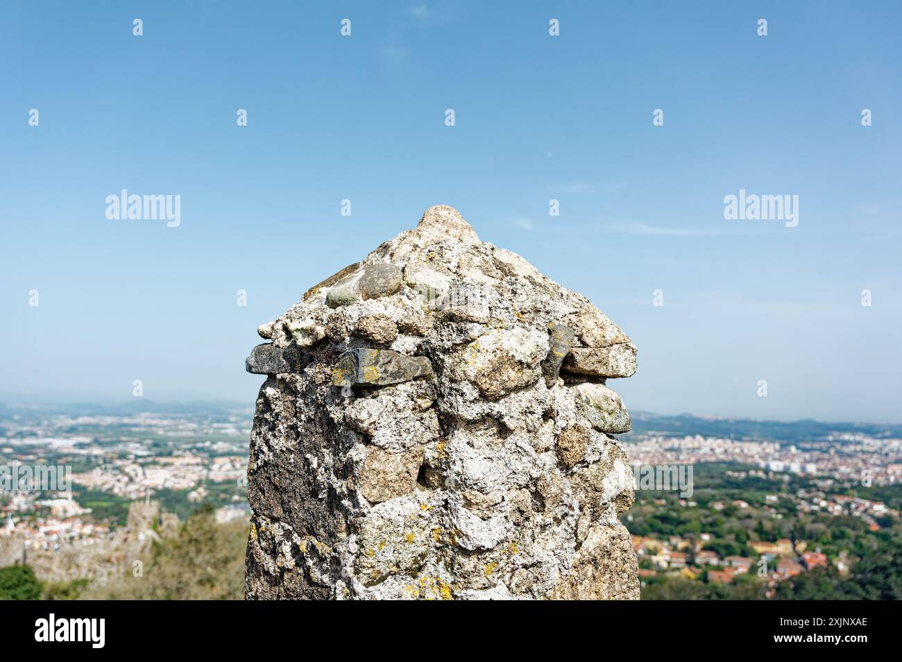 Nahaufnahme einer verwitterten Steinstruktur in der maurischen Burg in sintra mit Panoramablick auf die Landschaft darunter Stockfoto