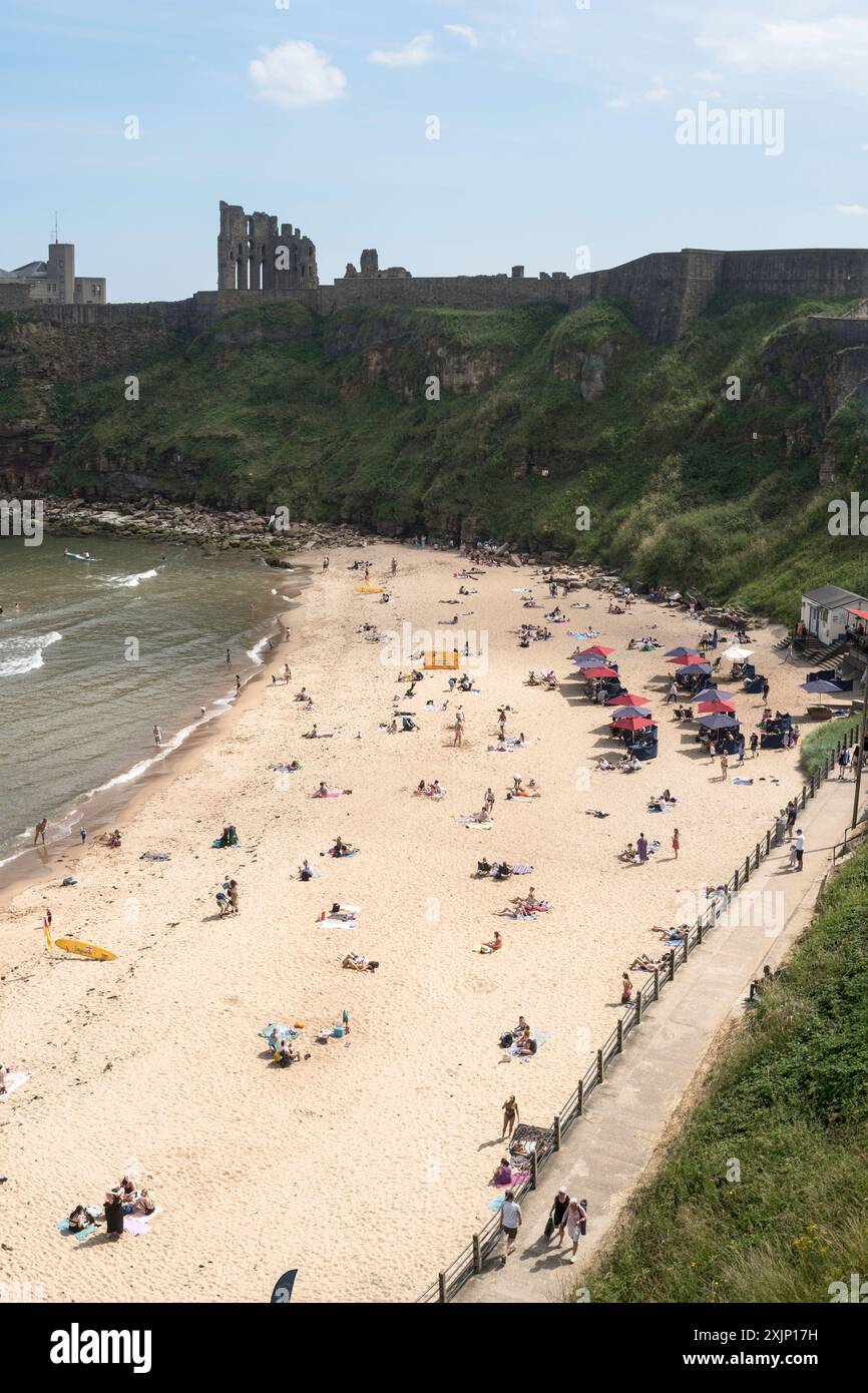 Menschen, die die Sommersonne am Strand von King Edward's Bay in Tynemouth, England, genießen Stockfoto