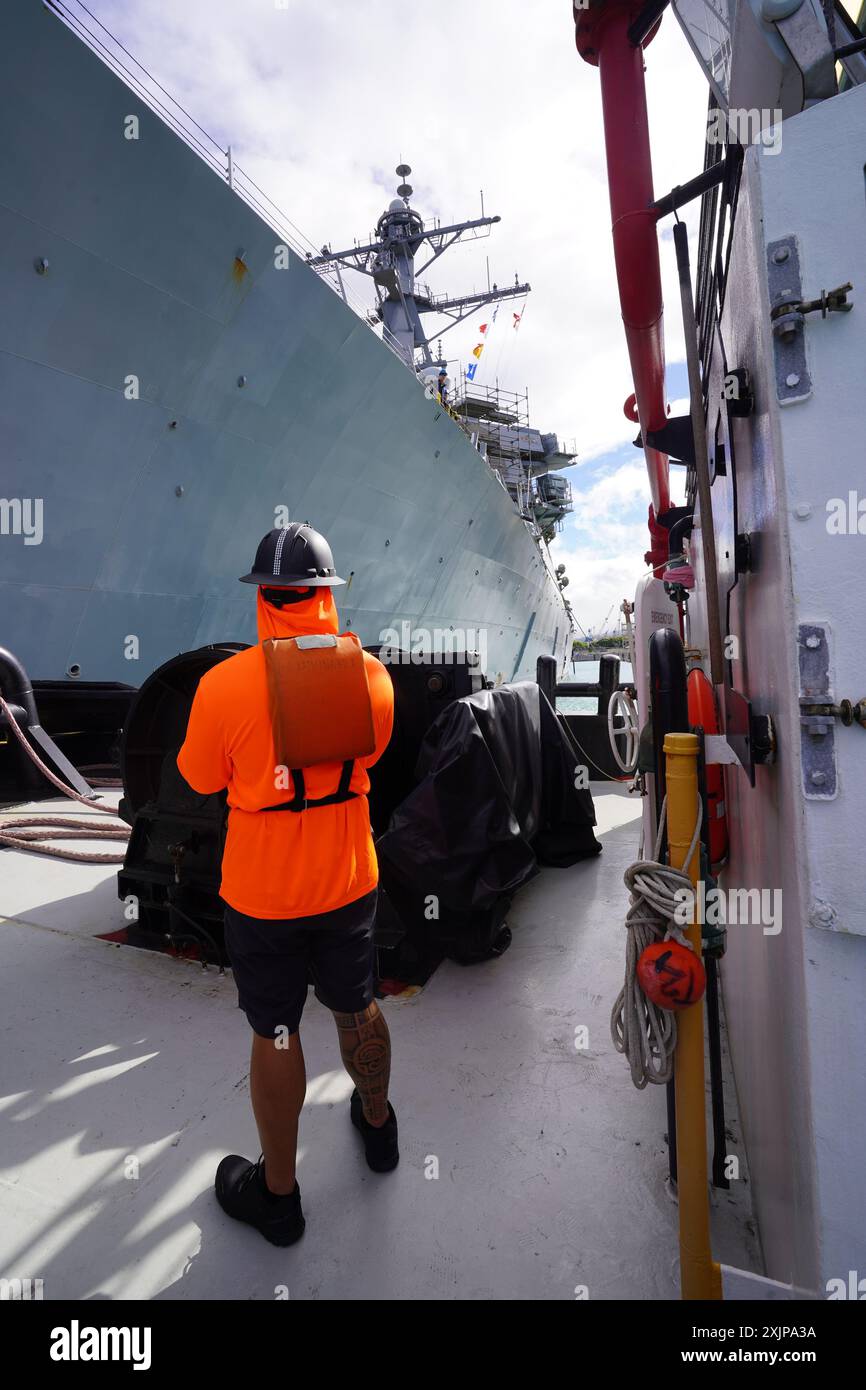 Kanale Salva, Deckhand mit ASD Kaimana Hila, beobachtet vom Schlepper aus, wie der Arleigh Burke-Klasse-Raketenzerstörer USS Hopper (DDG 70) am 27. Juni 2024 in Dry Dock 4, Pearl Harbor Naval Shipyard and Intermediate Maintenance Facility, Hawaii, eintrifft. Hopper hat eine Restricted Availability für das Trockendocking ausgewählt, die voraussichtlich im August 2025 abgeschlossen sein soll. Während dieser Zeit werden strukturelle, mechanische und Konservierungsfragen behandelt. PHNSY & IWF ist die größte und umfassendste Flottenreparatur- und -Wartungsanlage zwischen der Westküste der USA und dem Fernen Osten und bietet eine leistungsfähige, r Stockfoto