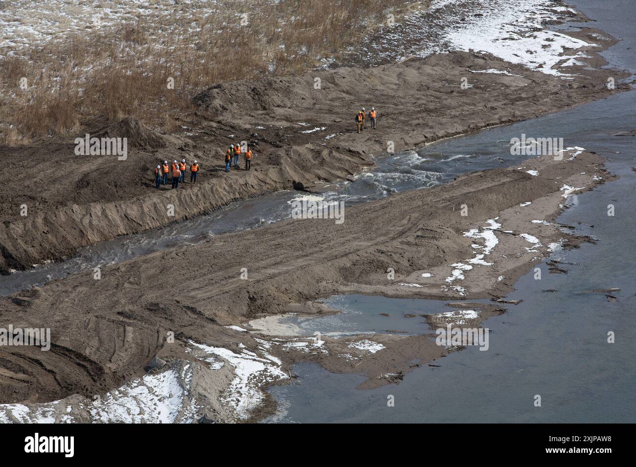 Mitarbeiter beobachten, wie sich der Kanal vertieft. Rapids beginnen am oberen Ende des Kanals, wenn der Strom steigt. Das Abziehen des Behälters führt zu Schmutzflecken. Stockfoto