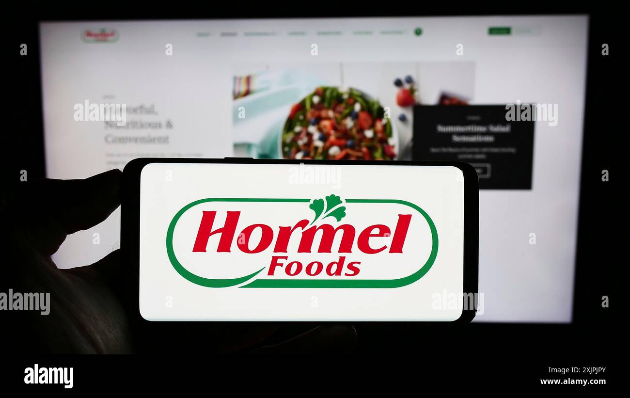 Stuttgart, Deutschland, 07.02.2023: Person, die ein Smartphone mit dem Logo des US-amerikanischen Lebensmittelunternehmens Hormel Foods Corporation auf dem Bildschirm vor der Website hält. Fokus Stockfoto