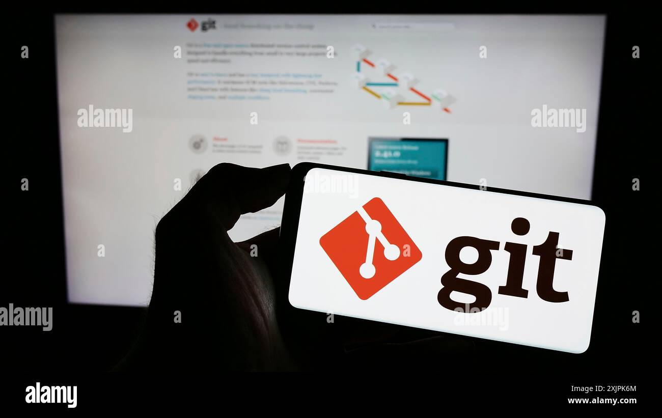 Stuttgart, Deutschland, 07.09.2023: Person, die ein Mobiltelefon mit dem Logo des verteilten Versionskontrollsystems Git auf dem Bildschirm vor der Webseite hält. Konzentrieren Sie sich auf Stockfoto