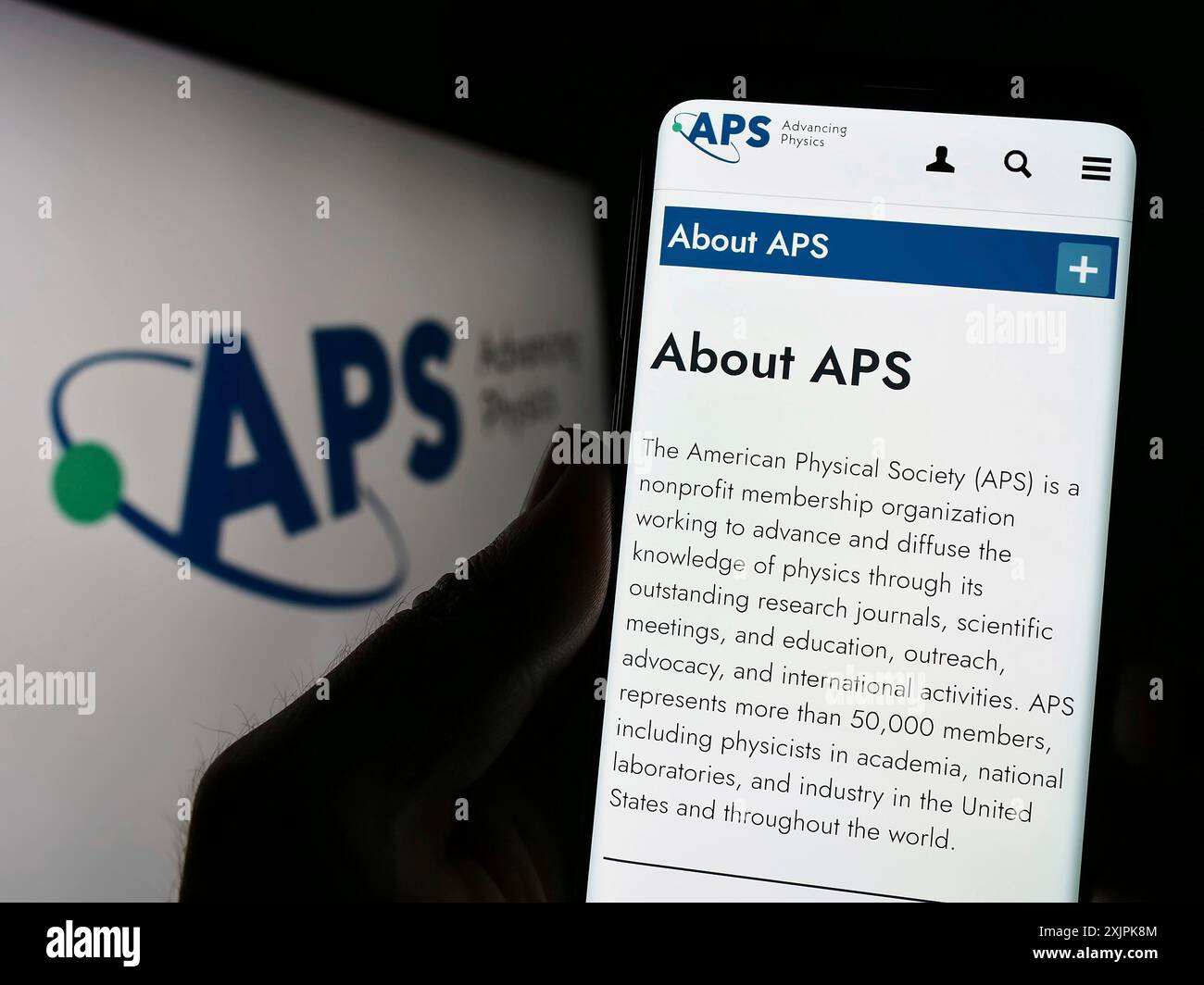 Stuttgart, Deutschland, 07.09.2023: Person, die ein Mobiltelefon hält, mit Webseite der amerikanischen Organisation American Physical Society (APS) auf dem Bildschirm mit Logo. Fokus Stockfoto