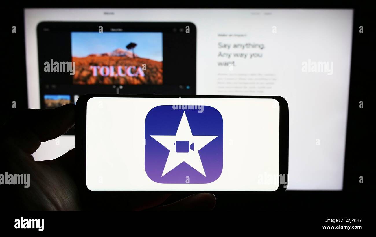 Stuttgart, Deutschland, 07.12.2023: Person, die ein Mobiltelefon mit dem Logo der Videobearbeitungssoftware iMovie (Apple Inc.) auf dem Bildschirm vor der Webseite hält. Fokus Stockfoto