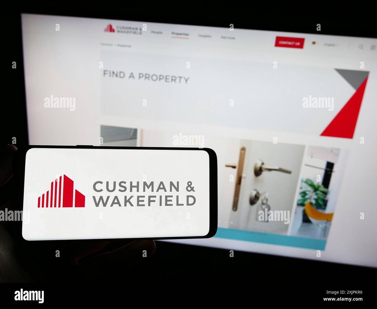 Stuttgart, 15.07.2023: Person, die ein Smartphone mit dem Logo der Immobilienfirma Cushman Wakefield plc auf dem Bildschirm vor der Website hält. Fokus Stockfoto