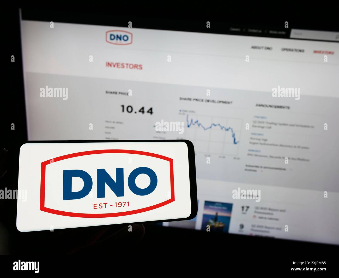 Stuttgart, Deutschland, 21.07.2023: Person, die ein Mobiltelefon mit dem Logo des norwegischen Öl- und Gasunternehmens DNO ASA auf dem Bildschirm vor dem Business Web hält Stockfoto