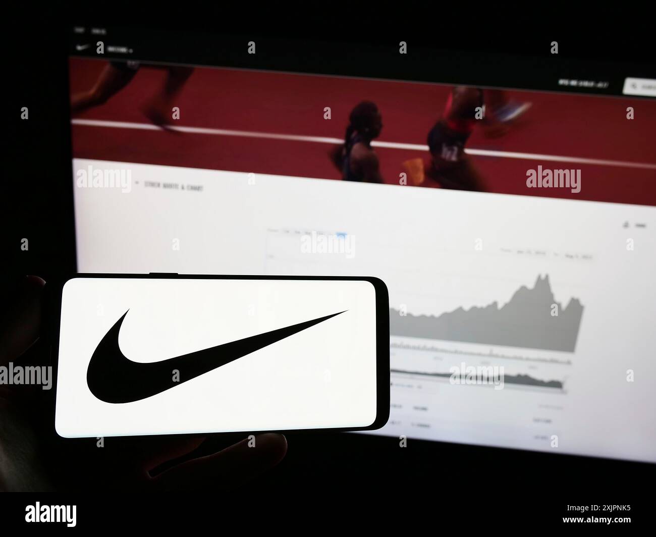Stuttgart, Deutschland, 08.06.2023: Person, die ein Mobiltelefon mit dem Logo des amerikanischen Sportbekleidungsunternehmens Nike Inc. Auf dem Bildschirm vor dem Business Web hält Stockfoto