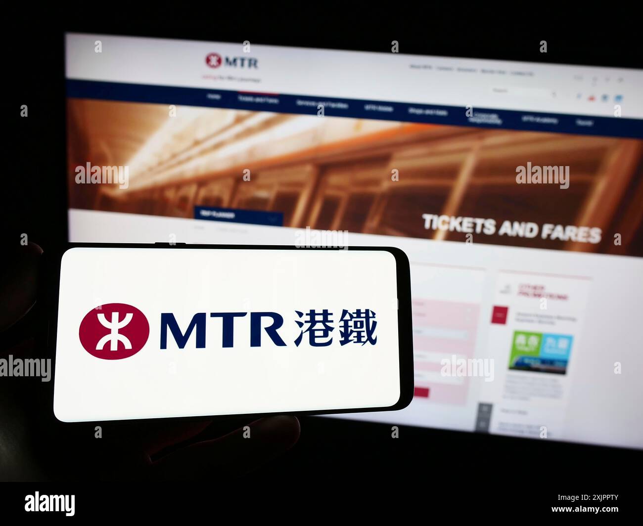 Stuttgart, Deutschland, 16.08.2023: Person, die ein Smartphone mit dem Logo der chinesischen Eisenbahngesellschaft MTR Corporation Limited auf dem Bildschirm vor der Website hält. Stockfoto