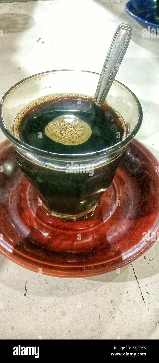 Ein Glas heißer schwarzer Kaffee auf einem kleinen Teller Stockfoto