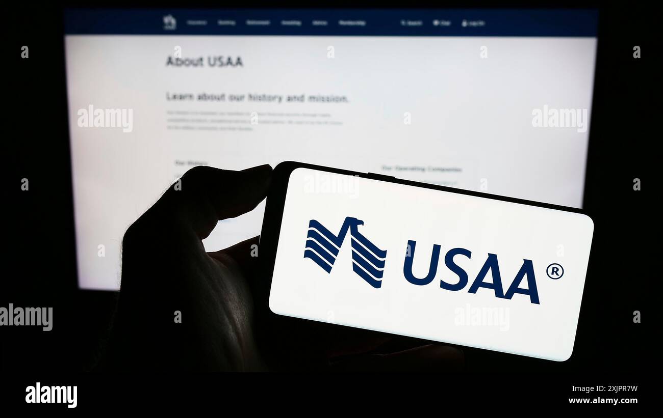 Stuttgart, Deutschland, 20.08.2023: Person, die ein Smartphone mit dem Logo der United Services Automobile Association (USAA) auf dem Bildschirm vor der Website hält. Stockfoto