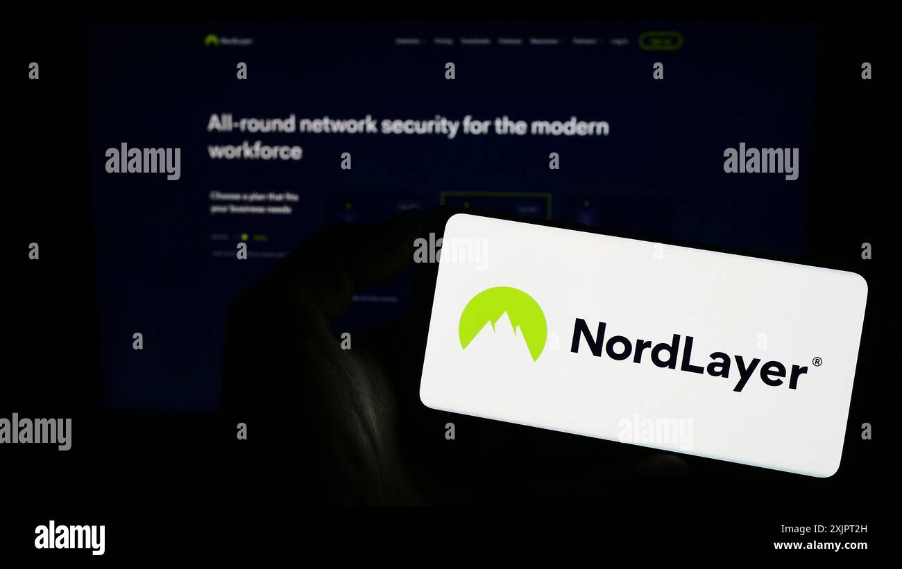 Stuttgart, Deutschland, 09.02.2023: Person, die ein Mobiltelefon mit dem Logo des Netzwerkzugangssicherheitsdienstes NordLayer auf dem Bildschirm vor dem Firmenweb hält Stockfoto