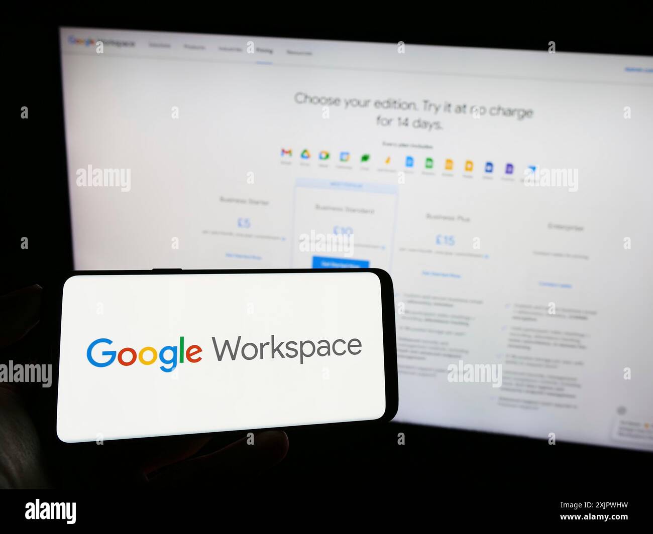 Stuttgart, Deutschland, 23.09.2023: Person, die ein Mobiltelefon mit dem Logo der Business-App-Software Google Workspace auf dem Bildschirm vor dem Web des Unternehmens hält Stockfoto