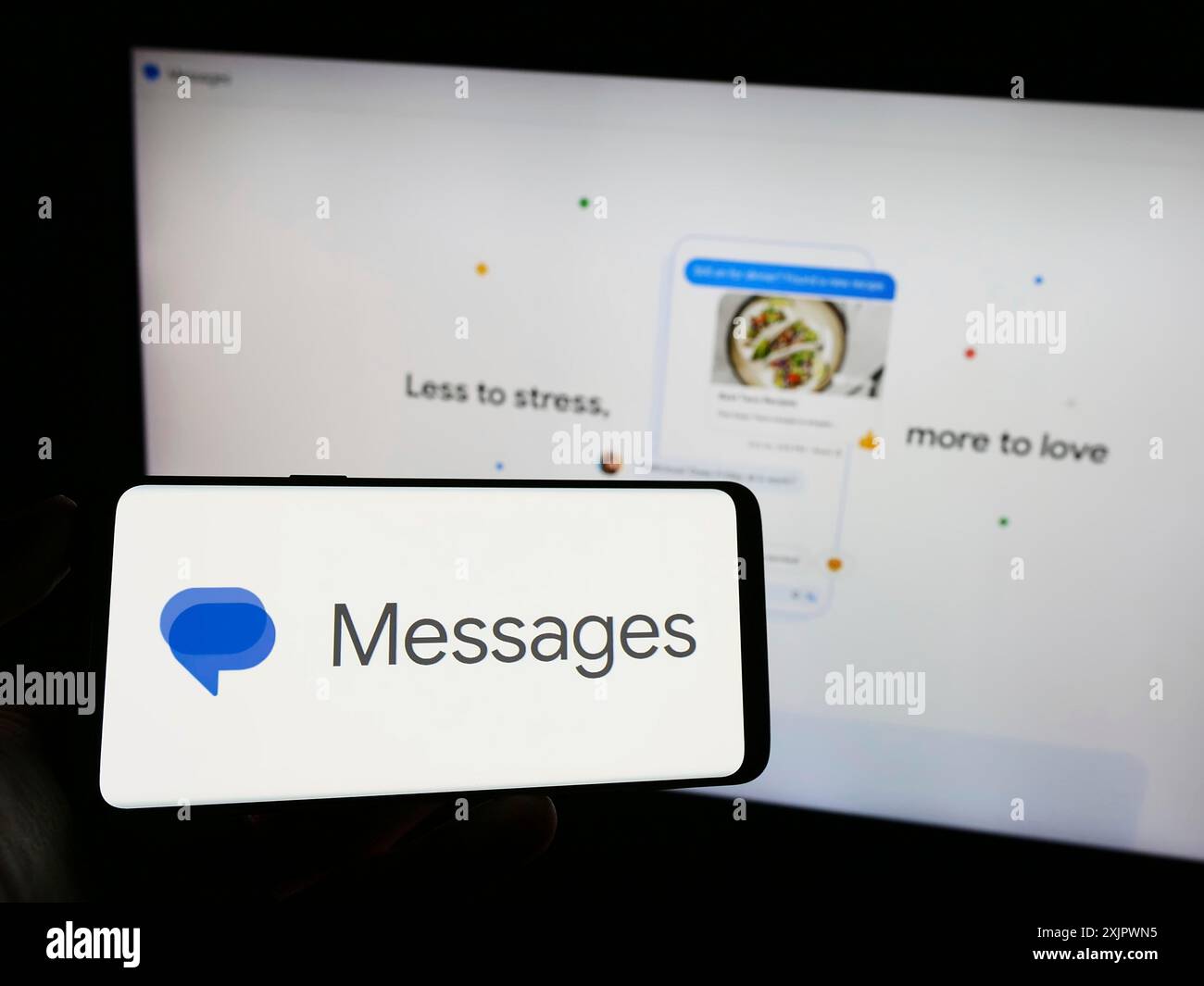 Stuttgart, Deutschland, 23.09.2023: Person, die ein Mobiltelefon mit dem Logo der Instant Messaging App Google Messages auf dem Bildschirm vor dem Business Web hält Stockfoto