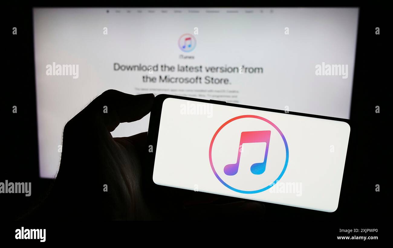 Stuttgart, 23.09.2023: Person, die ein Mobiltelefon mit dem Logo des Mediensoftwareprogramms Apple iTunes auf dem Bildschirm vor der Unternehmenswebseite hält. Stockfoto