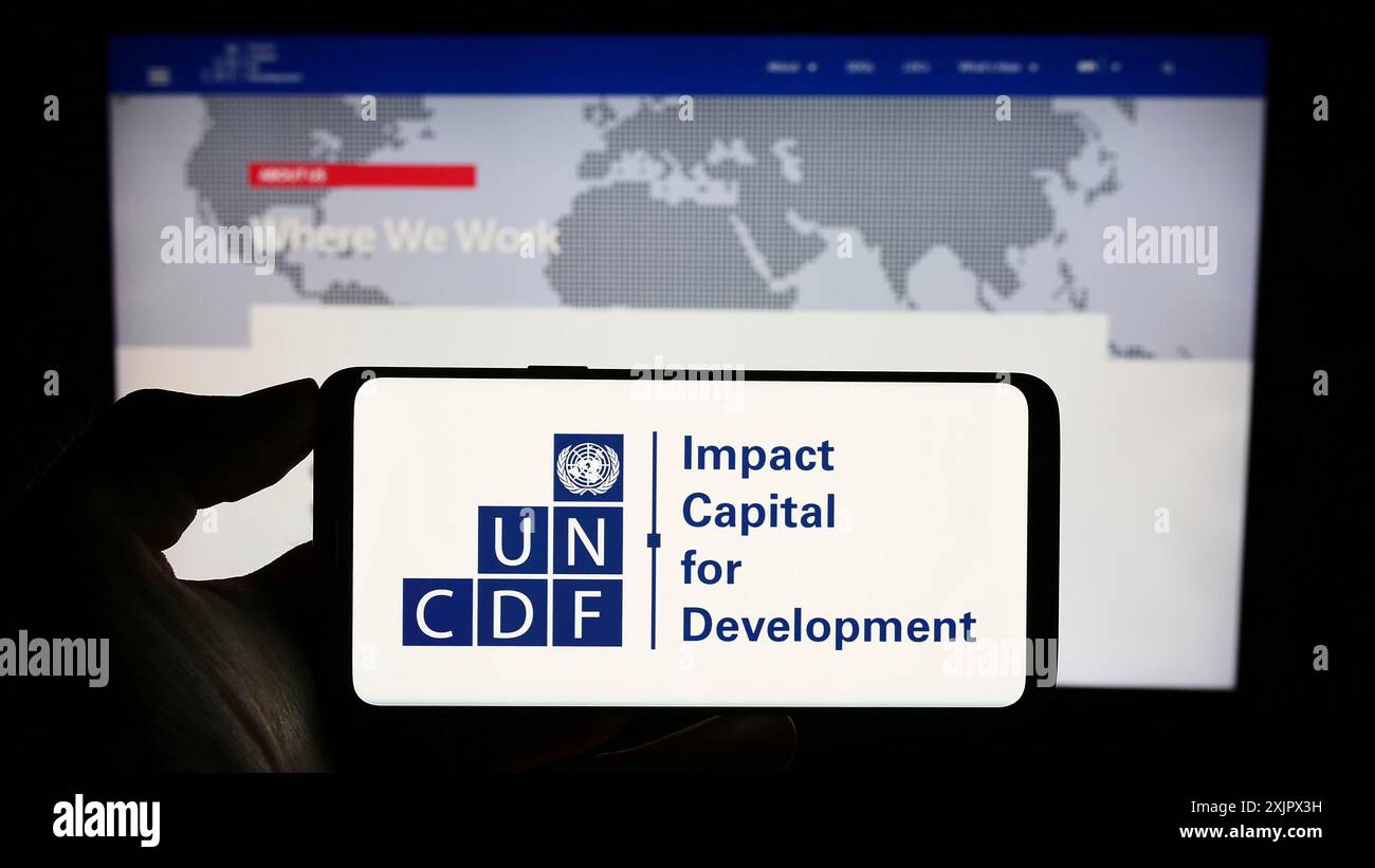 Stuttgart, Deutschland, 25.09.2023: Person mit Mobiltelefon mit Logo des Fonds der Vereinten Nationen für Kapitalentwicklung (UNCDF) vor der Webseite. Konzentrieren Sie sich auf Stockfoto
