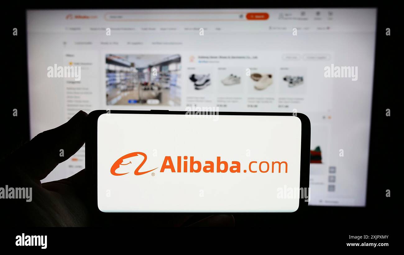 Stuttgart, Deutschland, 13.10.2023: Person, die ein Smartphone mit dem Logo der chinesischen B2B-E-Commerce-Plattform Alibaba.com vor der Website hält. Konzentrieren Sie sich auf Stockfoto