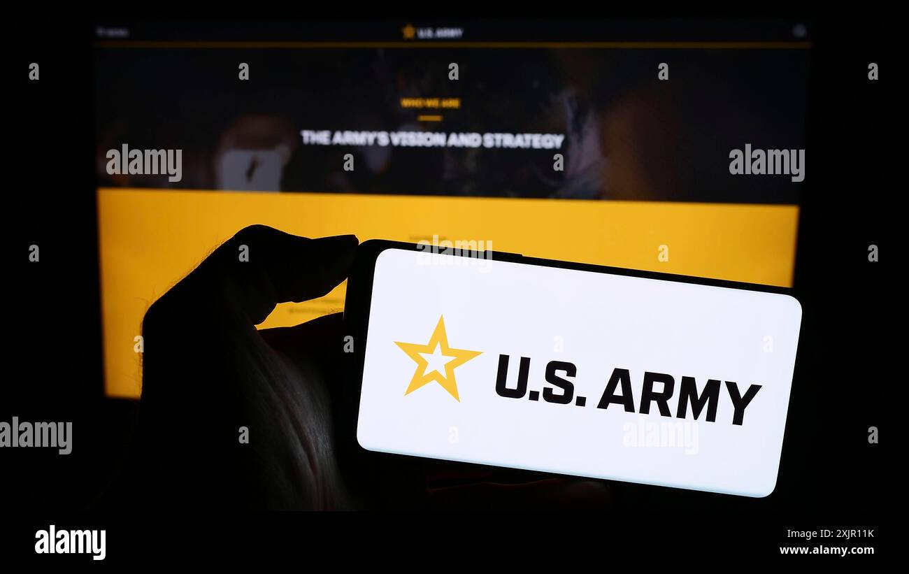 Stuttgart, Deutschland, 11.12.2023: Person, die ein Mobiltelefon mit Sternlogo der US Army vor der Webseite hält. Schwerpunkt auf dem Display des Telefons Stockfoto