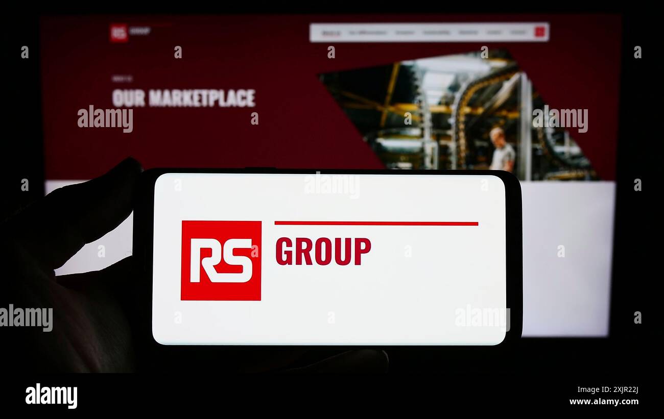 Stuttgart, 24.11.2023: Person, die ein Smartphone mit dem Logo des britischen Stromverteilers RS Group plc vor der Website hält. Stockfoto