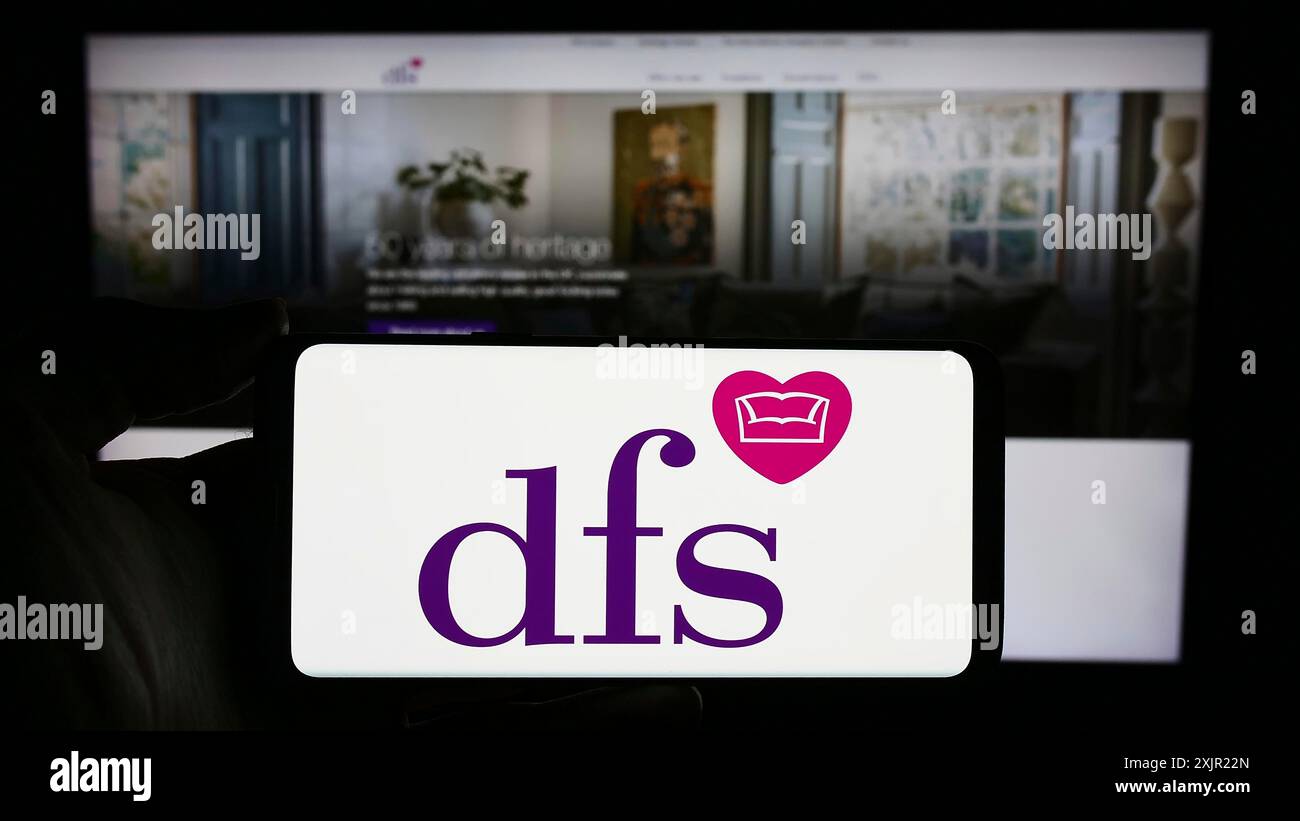 Stuttgart, 24.11.2023: Person mit Smartphone mit Logo des britischen Einzelhandelsunternehmens DFS Furniture plc vor der Website. Konzentrieren Sie sich auf das Telefon Stockfoto
