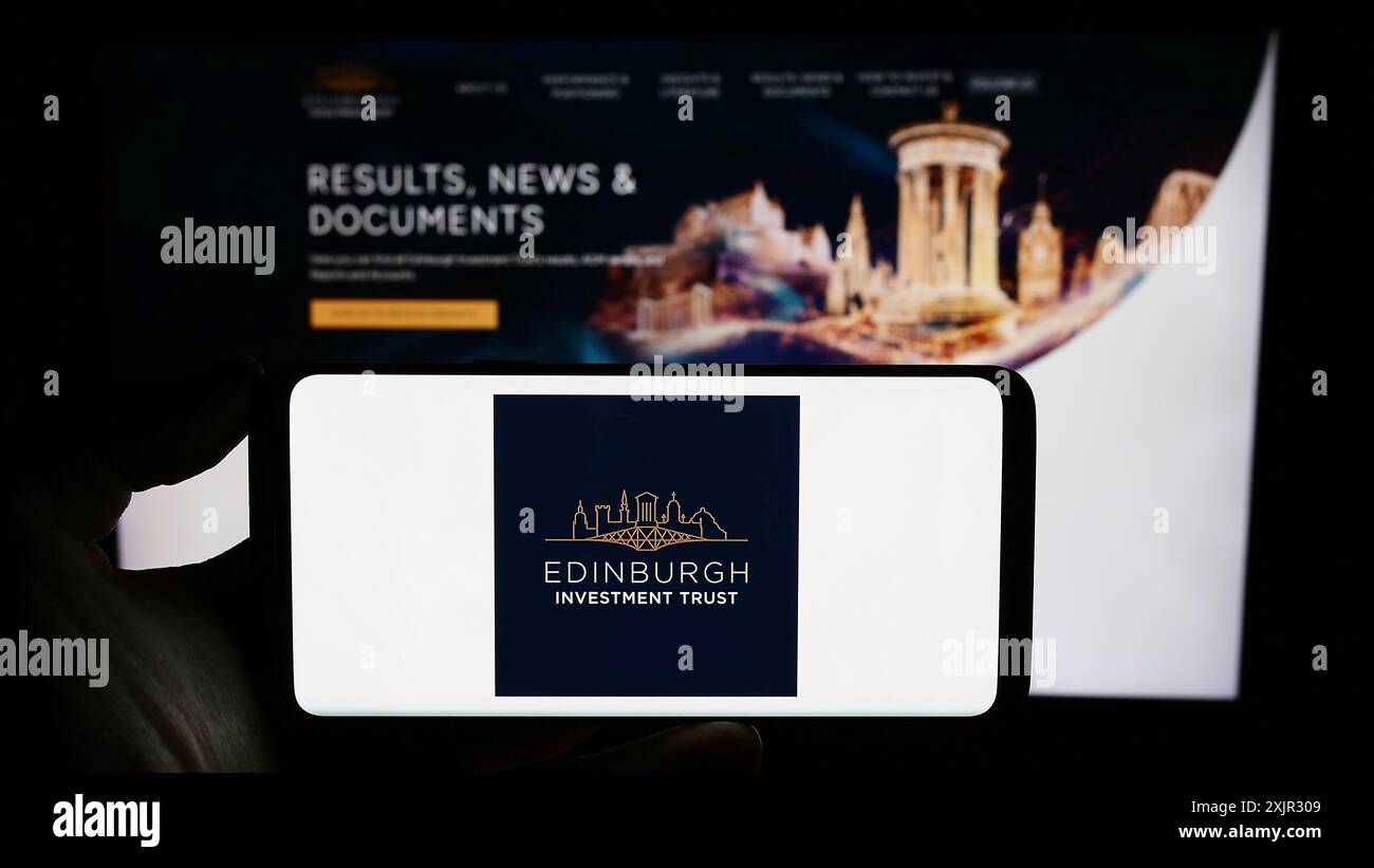 Stuttgart, Deutschland, 12.09.2023: Person, die ein Mobiltelefon mit dem Logo des britischen Unternehmens Edinburgh Investment Trust plc vor der Geschäftsstelle hält Stockfoto