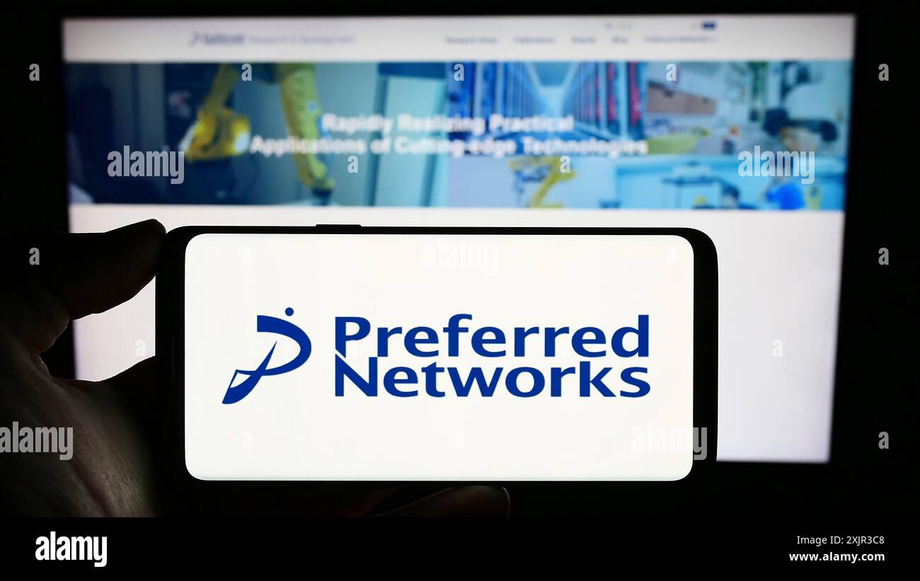 Stuttgart, 18.12.2023: Person, die ein Mobiltelefon mit dem Logo des Künstlichen Intelligenz-Unternehmens Preferred Networks Inc. Vor der Webseite hält. Stockfoto