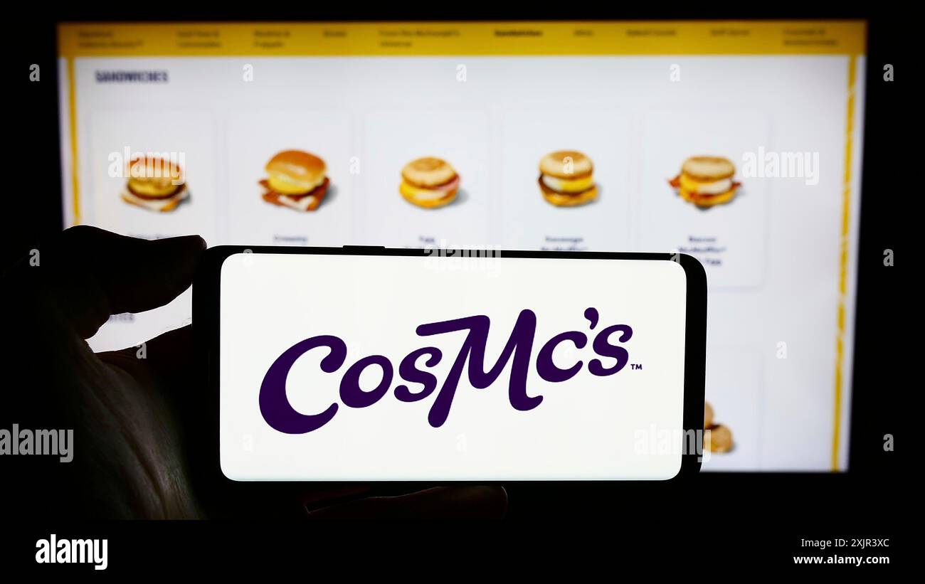 Stuttgart, 28.12.2023: Person, die ein Mobiltelefon mit dem Logo der US-amerikanischen Fastfood-Kette CosMc's (McDonalds) vor der Webseite hält. Stockfoto