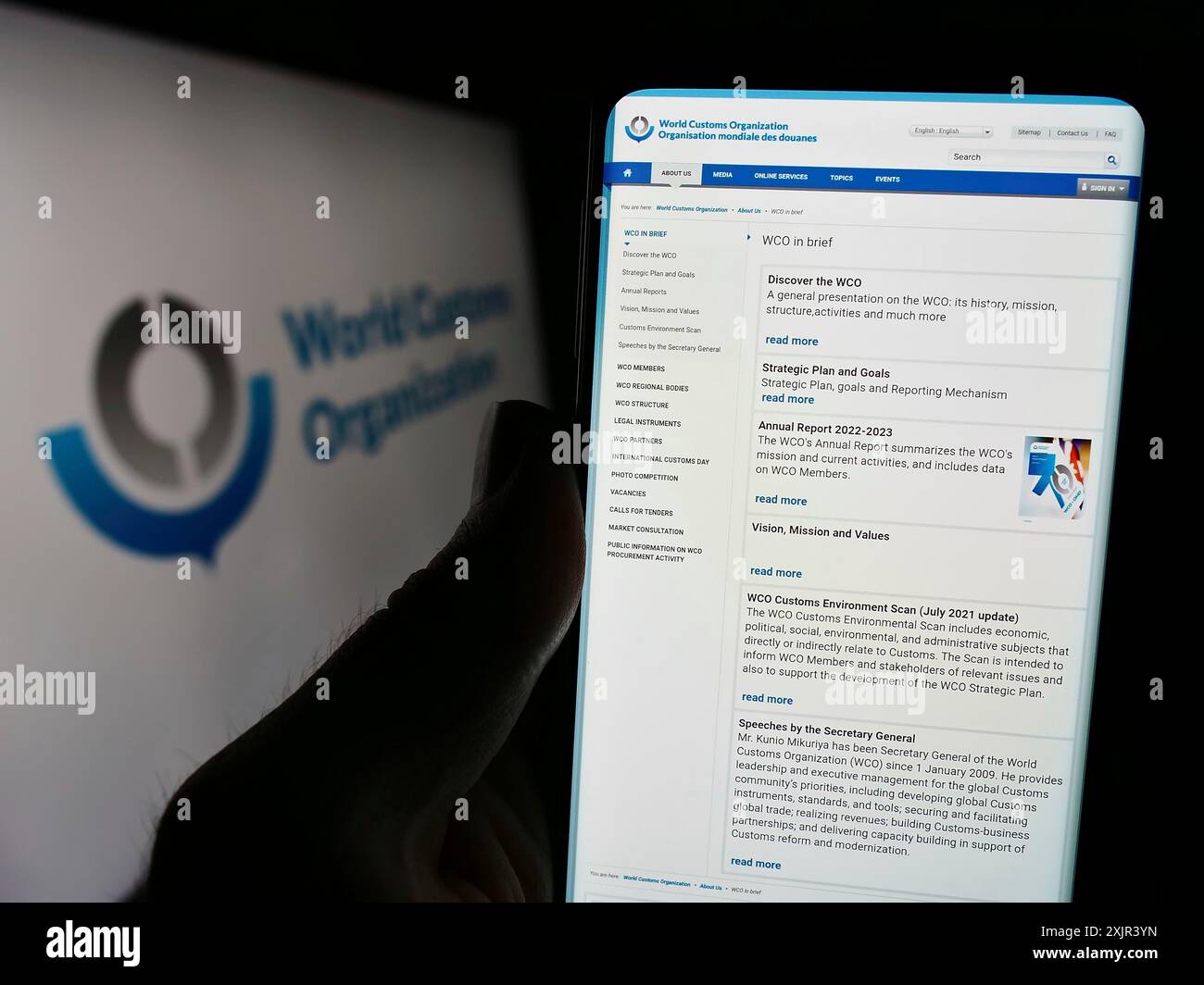 Stuttgart, 28.12.2023: Person, die ein Mobiltelefon hält und die Webseite der Weltzollorganisation (WZO) vor dem Logo steht. Konzentrieren Sie sich auf die Mitte des Telefons Stockfoto