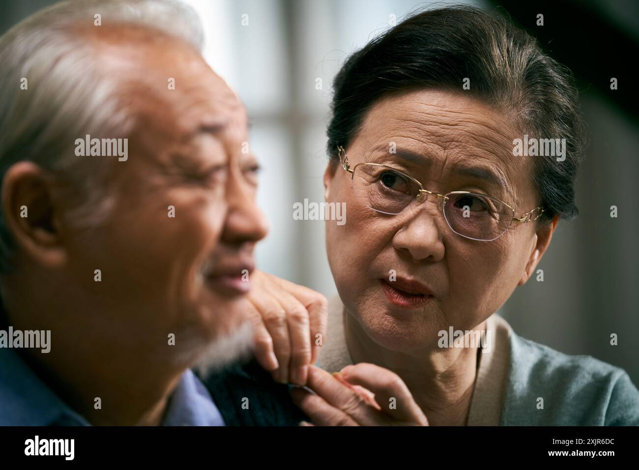 Liebevolle ältere asiatische Frau, die den Ehemann mit Sorge ansieht Stockfoto