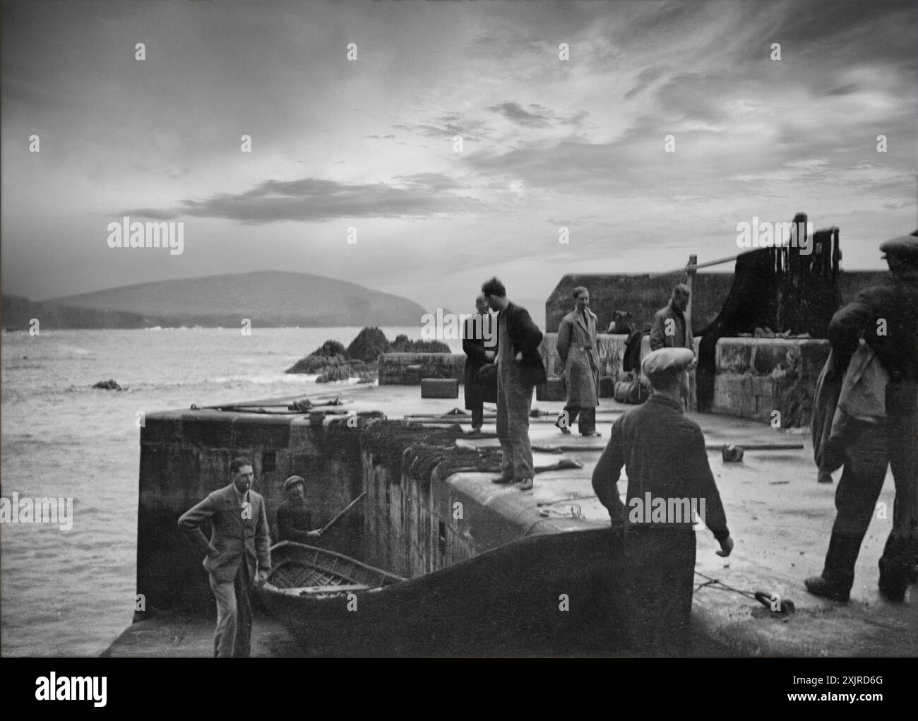 Zwanzig Jahre vor der Evakuierung der Blasket Islands vor der Dingle Peninsula, County Kerry in Irland, im Jahr 1954, machen sich die Inselbewohner von einem Currach an Land. Großer Blasket ist in der Ferne auf dem Foto von Ellen O’Connor (1874–1943) zu sehen. Stockfoto