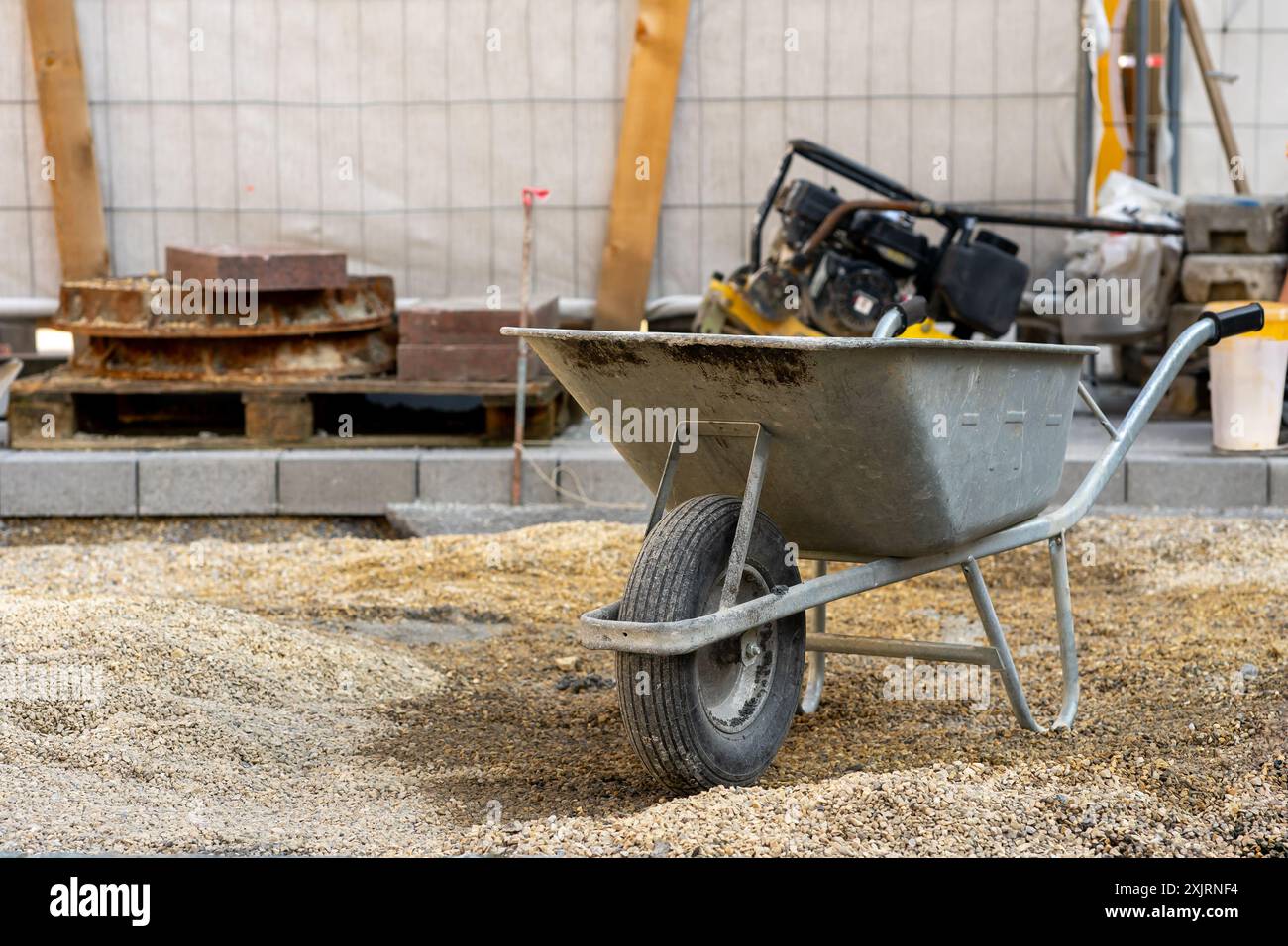 Eine graue Schubkarre und Zement auf der Baustelle. Stockfoto