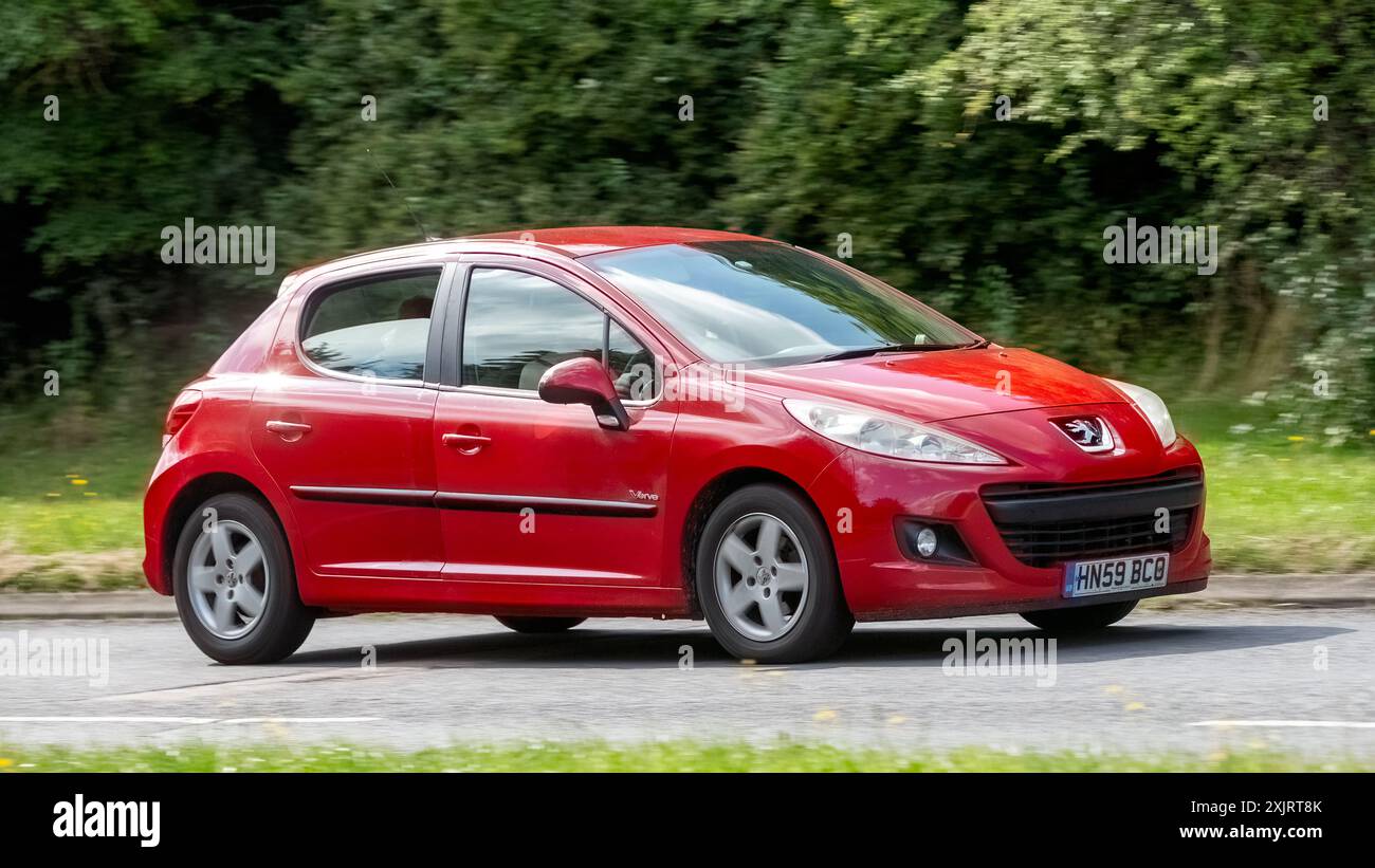 Milton Keynes, Großbritannien - 18. Juli 2024:2009 Red Peugeot 207 Auto fährt auf einer britischen Landstraße Stockfoto