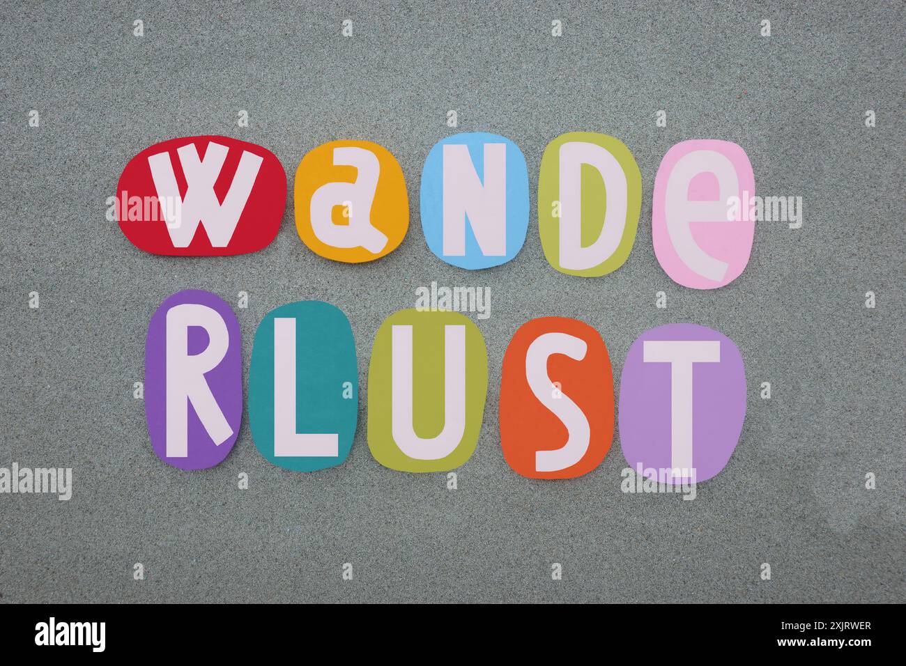 Fernweh ist ein starker Wunsch, die Welt zu erkunden oder zu erkunden, mit kreativem Text, der mit handgemalten mehrfarbigen Steinbuchstaben komponiert wurde Stockfoto