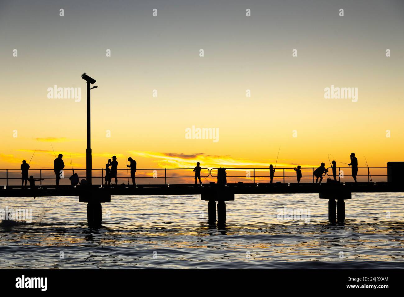 Leute fischen am Jurien Bay Pier bei Sonnenuntergang. Stockfoto