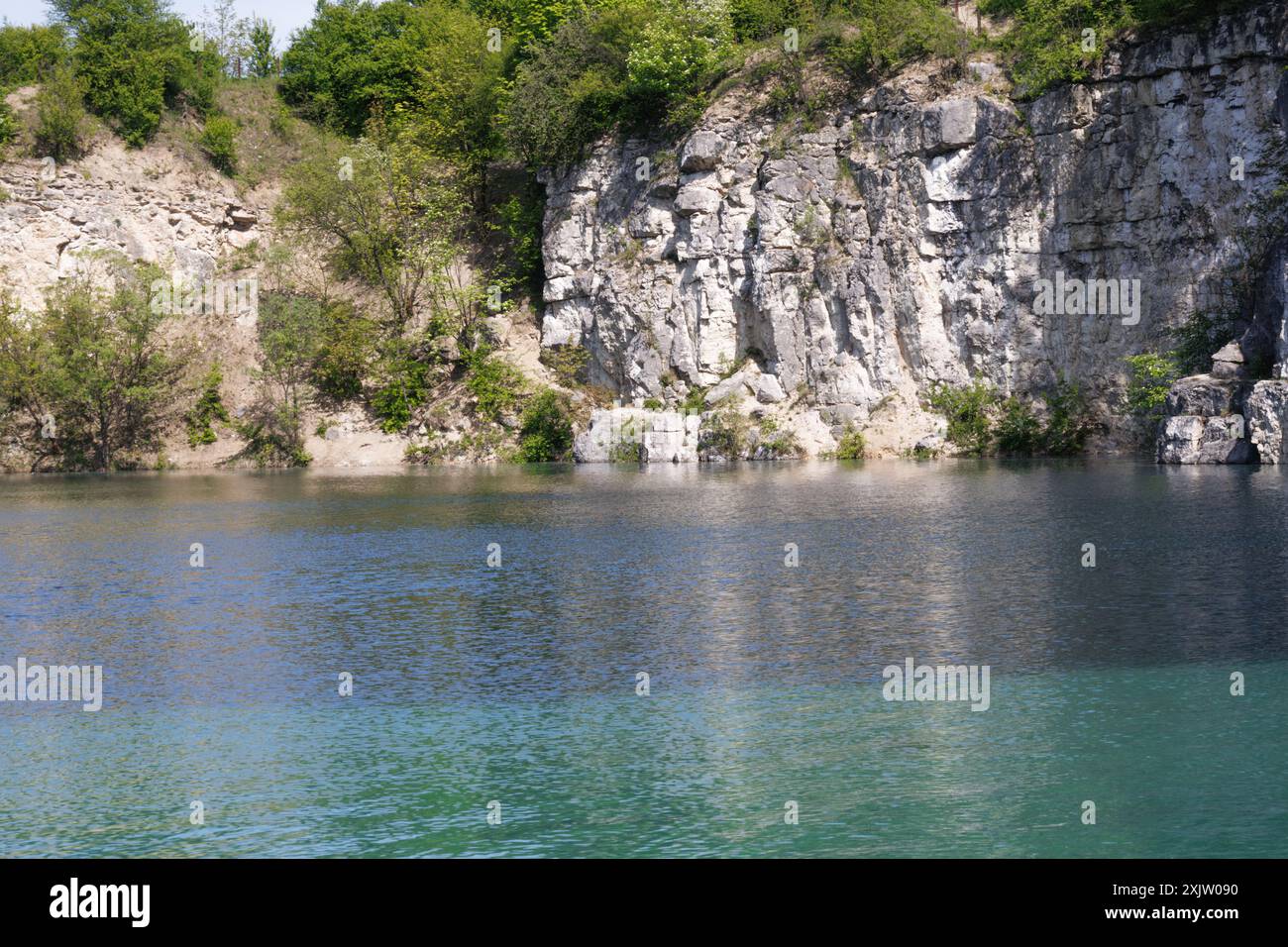 Ein wunderschöner türkisfarbener See mit Felsen und üppigem Grün, der den Charme der Landschaft unterstreicht. Stockfoto