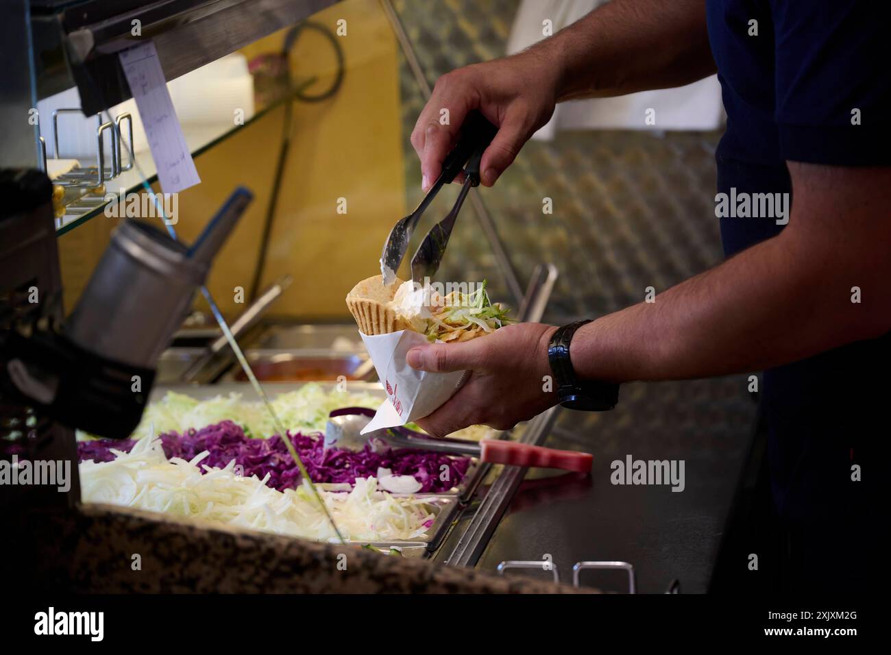 Eine Dönertasche wird befüllt ein Mitarbeiter eines Döner Schnellimbisses füllt eine Dönertasche. Zugesehen sind nur seine Unterarme, kein Gesicht. Veröffentlichungen nur für redaktionelle Zwecke. Foto: FotoPrensa Hattingen NRW *** Ein Dönersack wird gefüllt ein Mitarbeiter eines Dönersacks füllt einen Dönersack nur seine Unterarme sind sichtbar, kein Gesicht Publikationen nur für redaktionelle Zwecke Foto FotoPrensa Hattingen NRW Stockfoto