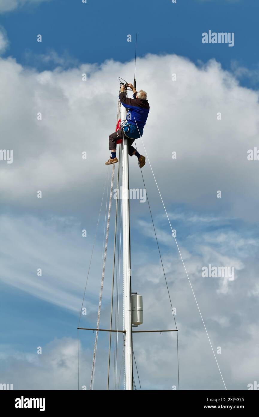 Matrose, Segler in Einem Bosuns Stuhl, der ein Anenometer auf Einem Stahlmast Einer Yacht repariert, Segelboot, Großbritannien Stockfoto