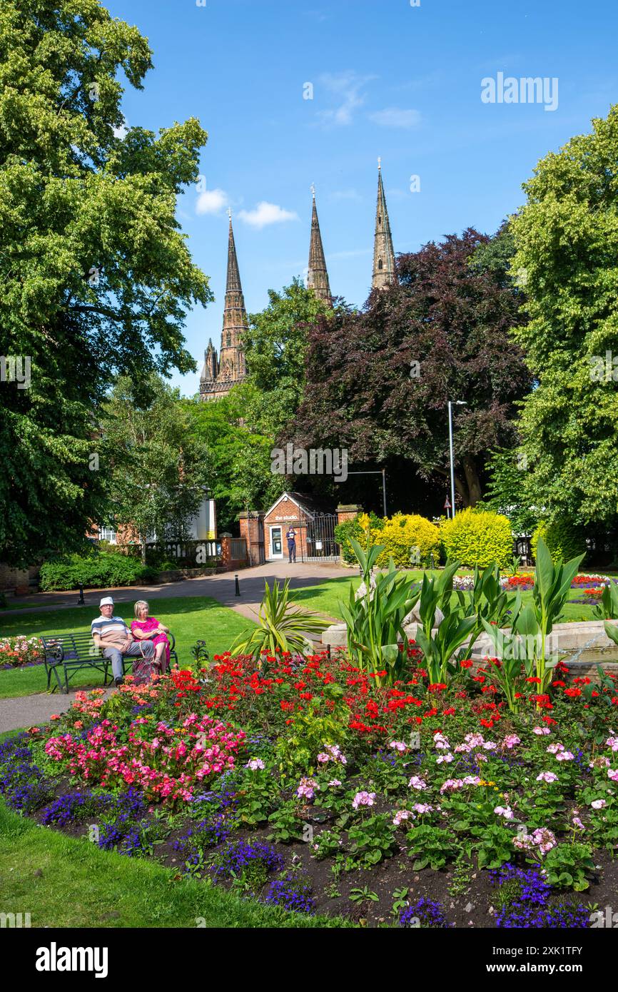 Paare genießen die Sommersonne in den formellen Blumengärten des Beacon Park Lichfield Staffordshire England UK mit der Kathedrale dahinter Stockfoto