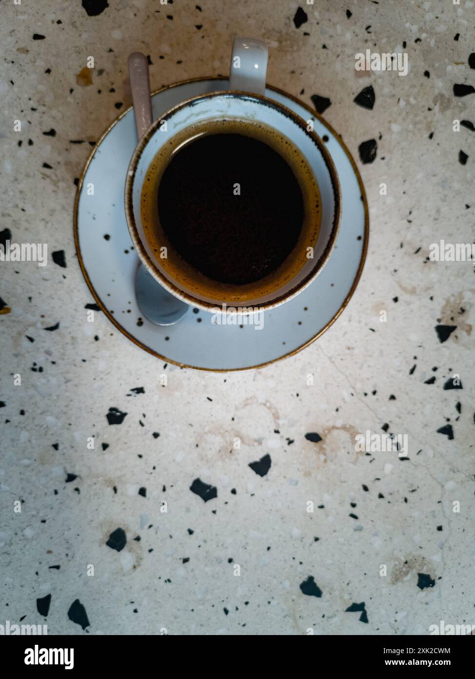 Kleine dekorative Tasse schwarzen Kaffees auf dem Tisch mit Terrazzo-Muster in einem kleinen Café Stockfoto