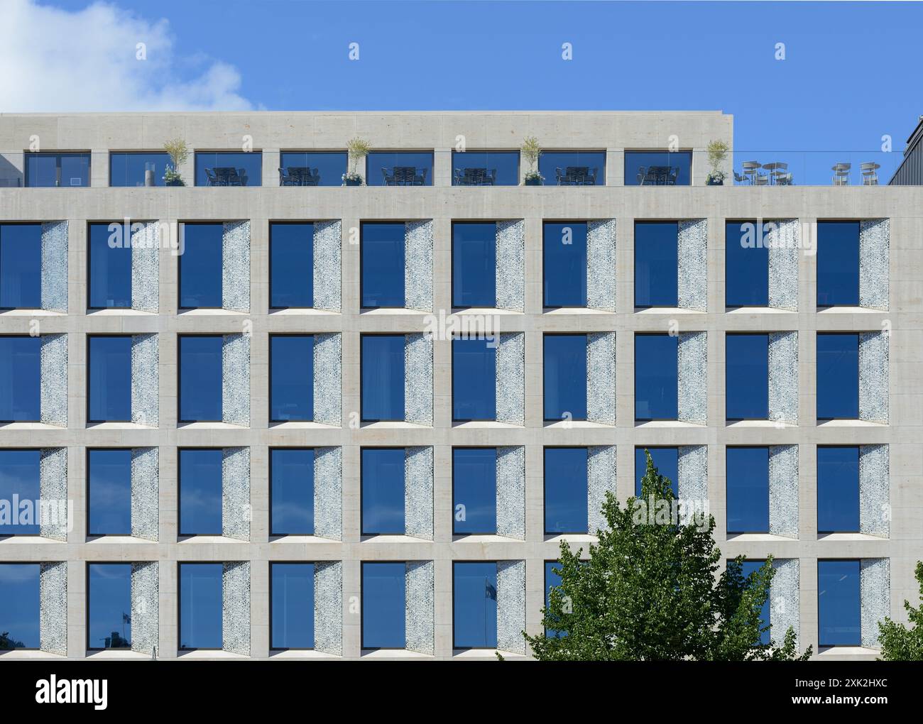 Ein modernes Bürogebäude mit einer symmetrischen Fassade mit großen blau getönten Glasfenstern in einer Betonkonstruktion. Das Design ist minimalistisch Stockfoto