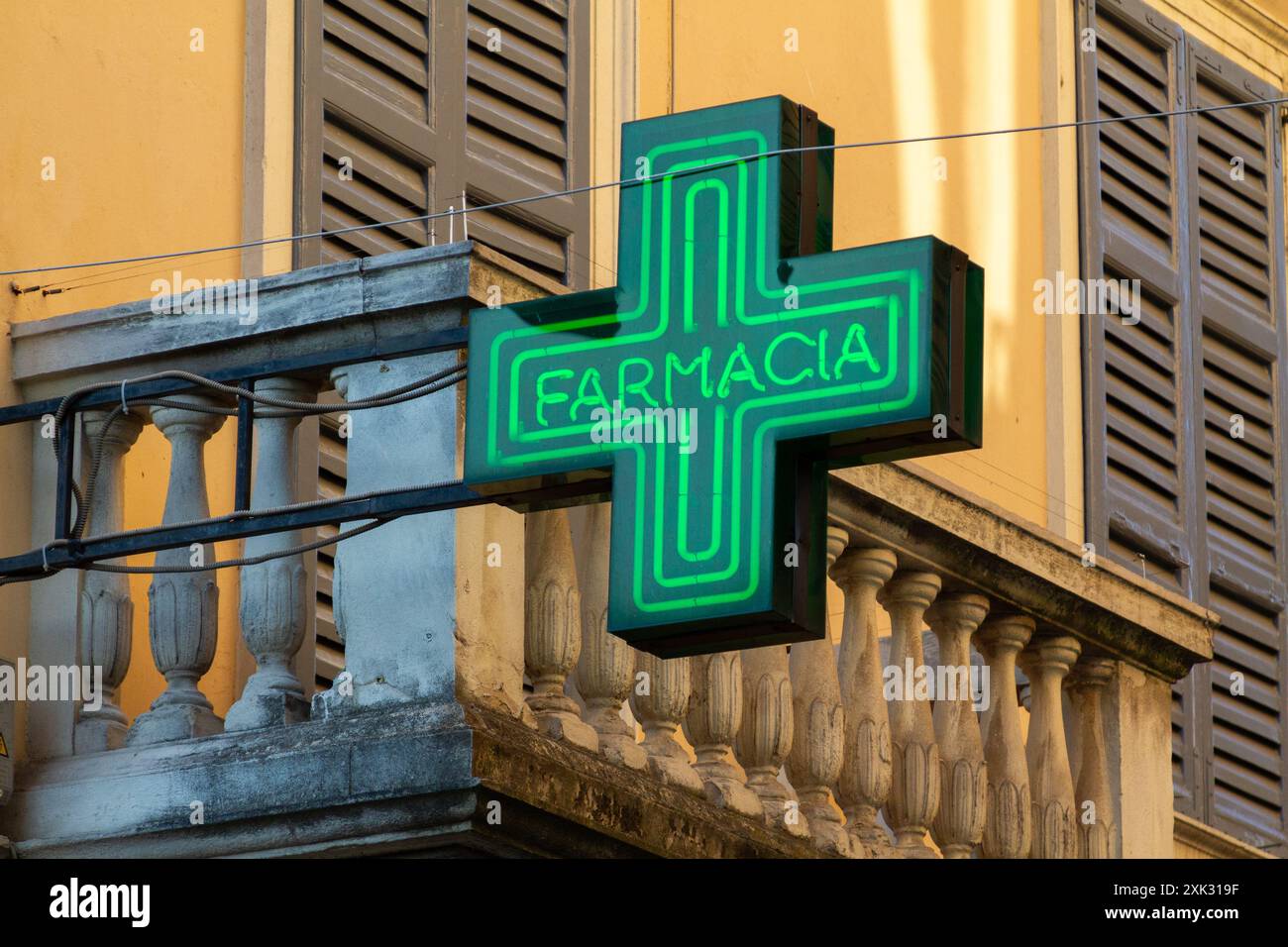 FARMACIA – ein grünes Neonapothekenkreuz – ein Schild über einer Apotheke in Italien. Stockfoto