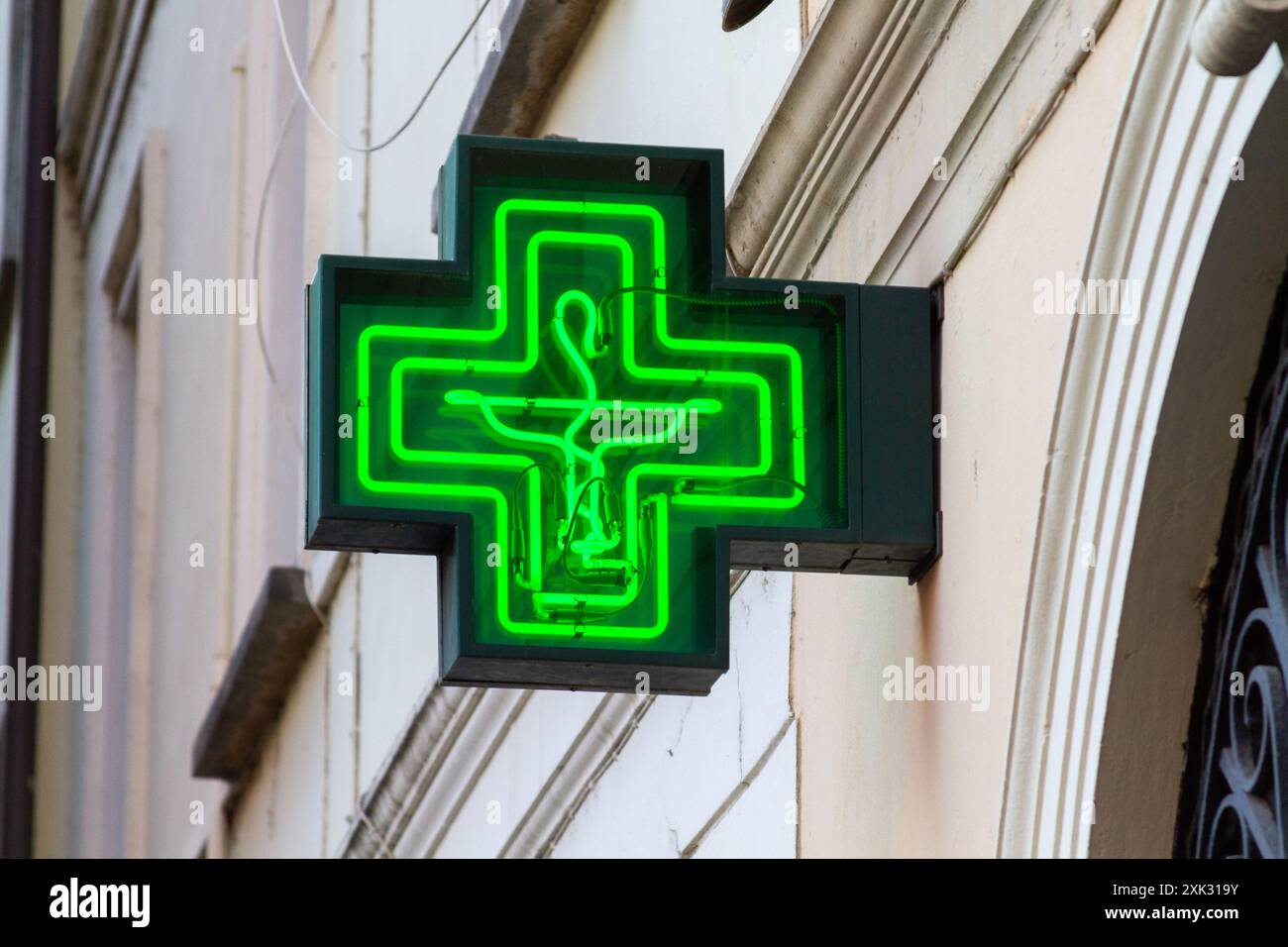 Ein grünes Neon-Apothekenkreuz (mit einer Schlange, die um einen Becher gewickelt ist) – ein Schild über einer Apotheke Stockfoto
