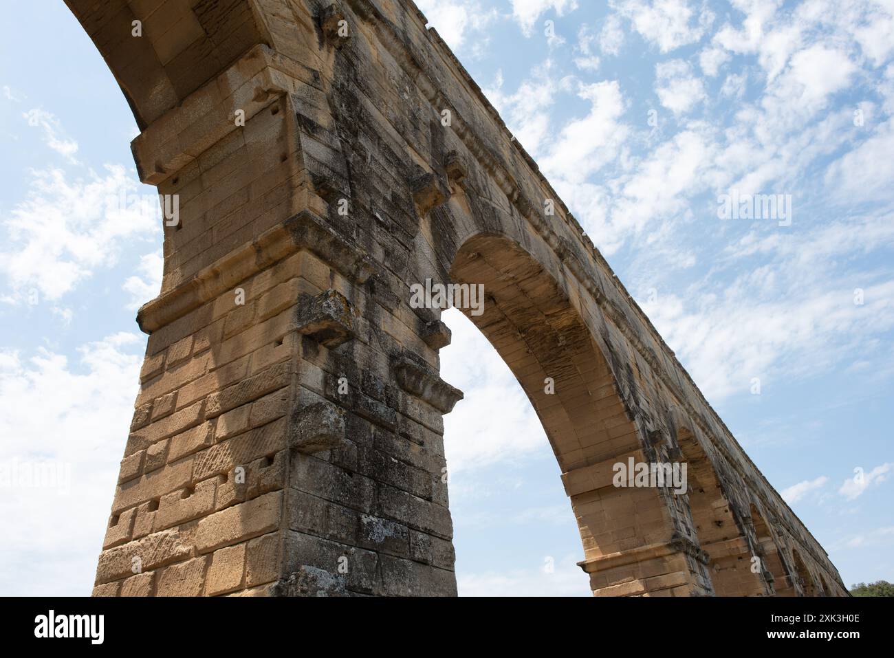 VERS-PONT-DU-GARD, Frankreich – der majestätische Pont du Gard, ein altes römisches Aquädukt und UNESCO-Weltkulturerbe, erstreckt sich über den ruhigen Fluss Gardon in Südfrankreich. Diese bemerkenswerte dreistöckige Brücke zeigt den Einfallsreichtum römischer Technik vor dem Hintergrund der malerischen mediterranen Landschaft. Stockfoto