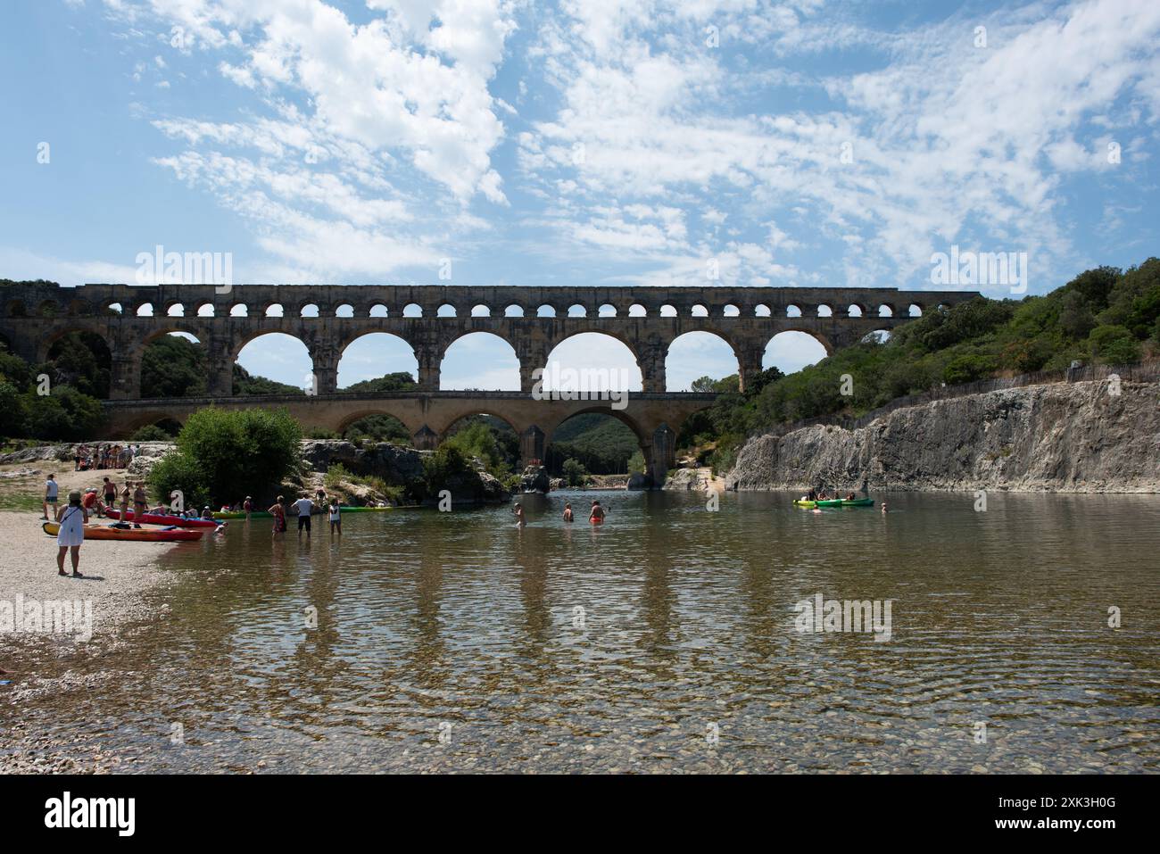 VERS-PONT-DU-GARD, Frankreich – der majestätische Pont du Gard, ein altes römisches Aquädukt und UNESCO-Weltkulturerbe, erstreckt sich über den ruhigen Fluss Gardon in Südfrankreich. Diese bemerkenswerte dreistöckige Brücke zeigt den Einfallsreichtum römischer Technik vor dem Hintergrund der malerischen mediterranen Landschaft. Stockfoto