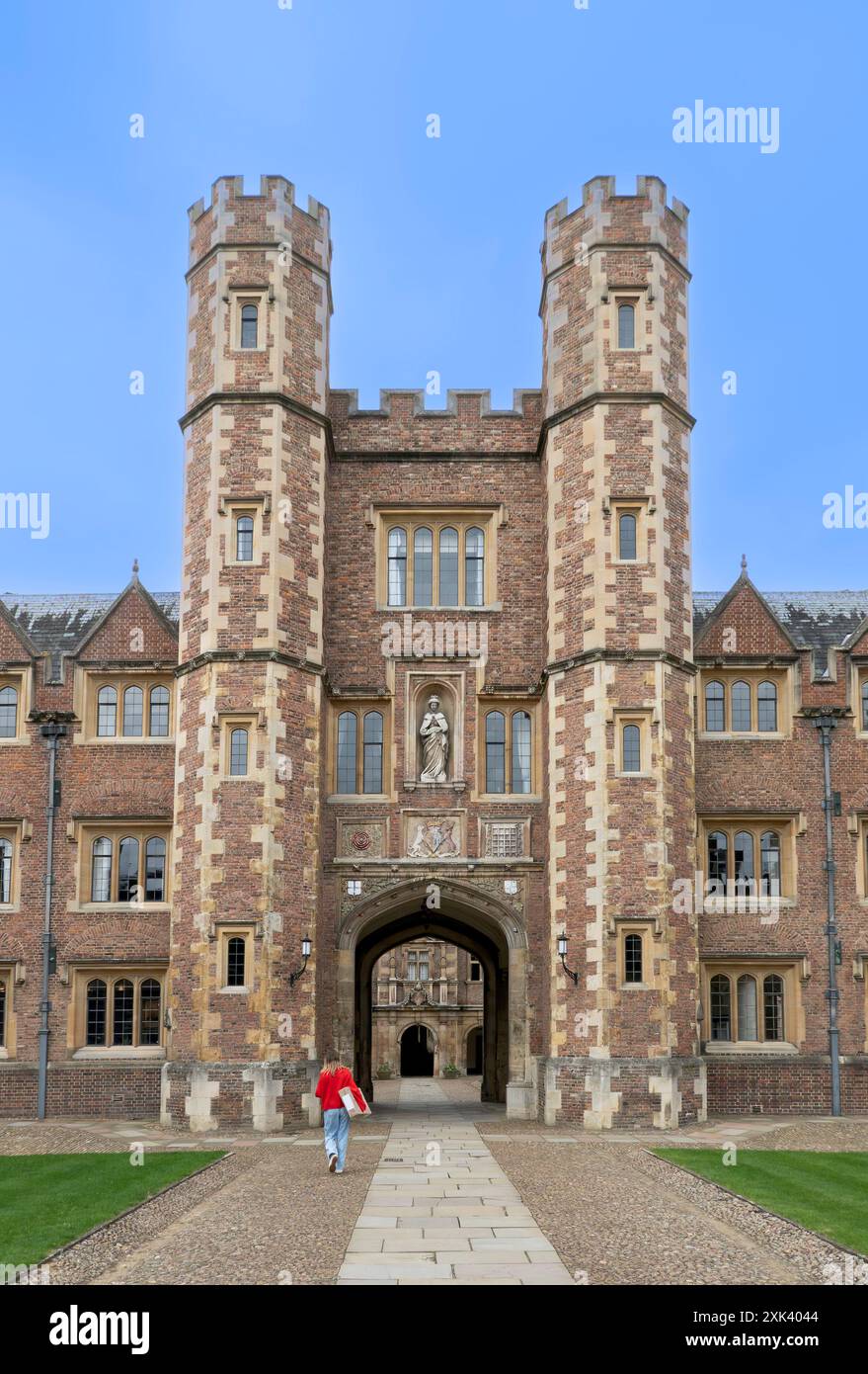 Blonde Frau in rotem Pullover und blauer Jeans mit einem Paket im King's College, Cambridge, Großbritannien Stockfoto