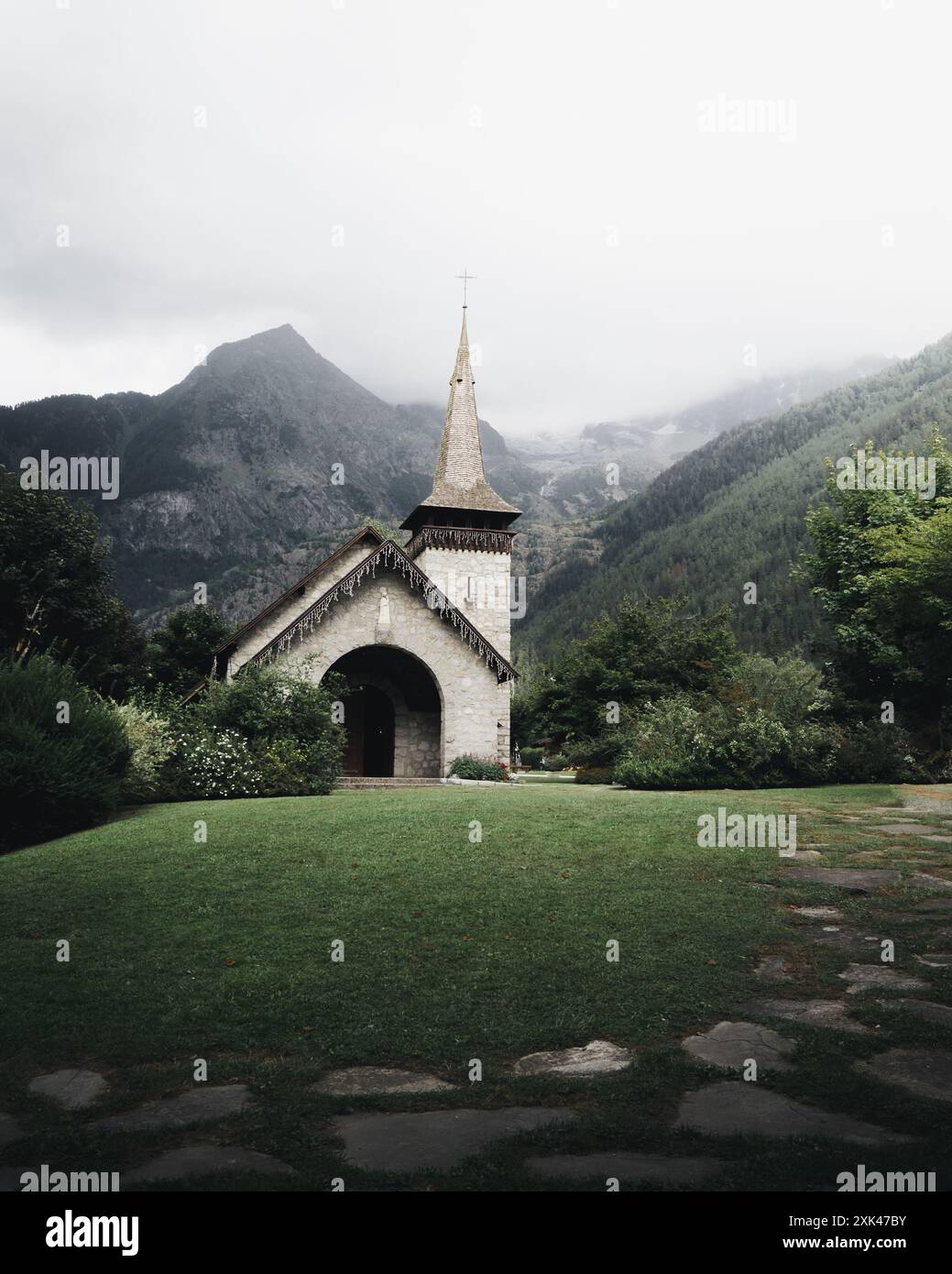 Eine bezaubernde Kirche vor dem Hintergrund nebeliger Berge. Les Praz, Chamonix, Frankreich Stockfoto
