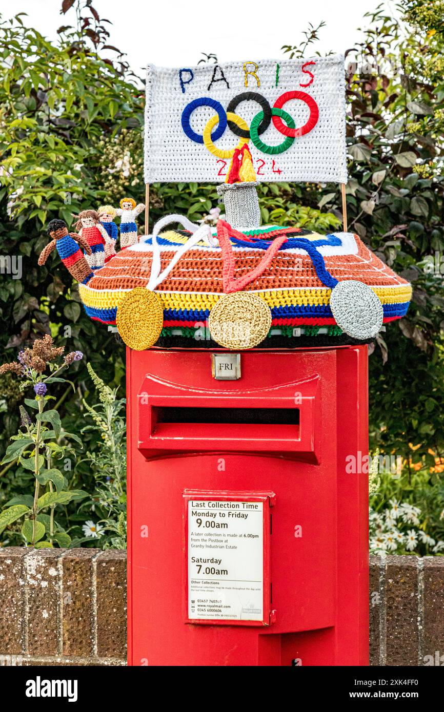 Farbenfrohe Strickkiste zur Feier der Olympischen Spiele 2024 in Paris mit Häkelmedaillen, Athleten, Flammen und Olympischen Ringen, Weymouth, Dorset Stockfoto