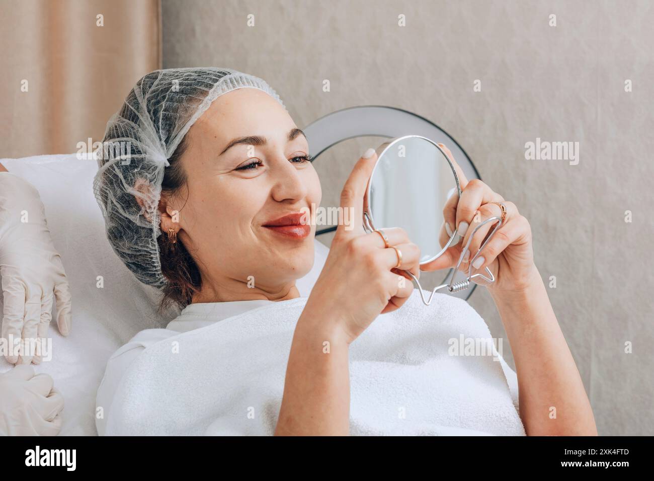 Die Frau beobachtet sorgfältig die Auswirkungen ihrer neuesten Hautpflege und untersucht ihren erfrischten Teint mit einem Spiegel Stockfoto