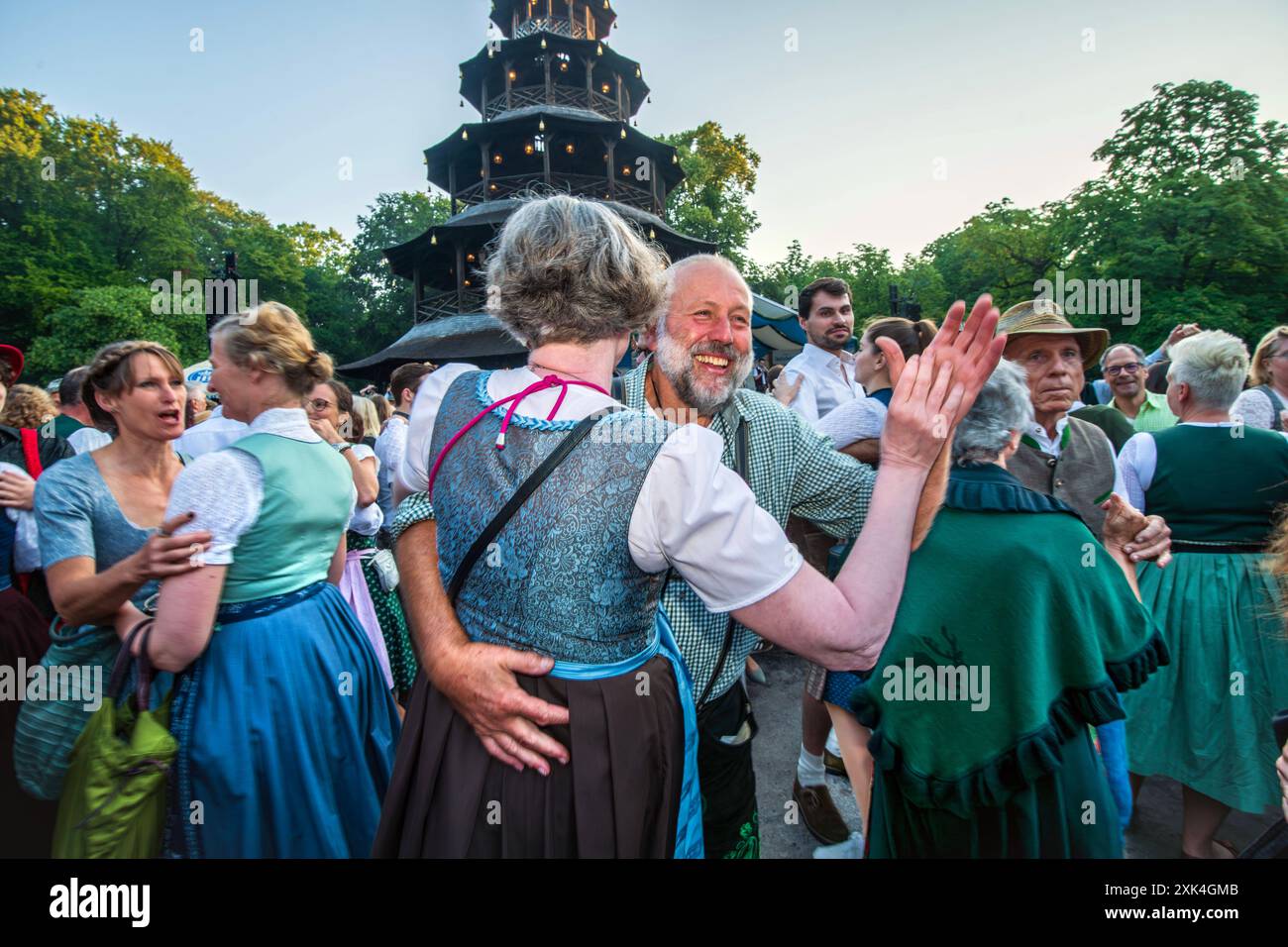 Kocherlball am Chinesischen Turm, hunderte Paare tanzen zur bayerischen Musik, morgens um 6:15 Uhr, München, 21. Juli 2024 Deutschland, München, 21. Juli 2024, hunderte Paare tanzen zur bayerischen Musik, morgens um 6:15 Uhr, eine Dreiviertelstunde nach Sonnenaufgang, Kocherlball am Chinesischen Turm, Englischer Garten, Musikkapelle Quetschnblech spielt auf, Besucher feiern und tanzen früh morgens zu bayerischer Musik, tragen Tracht, Tradition entstand im 19. Jahrhundert, als Hauspersonal, Dienstboten und Köchinnen in den frühen Morgenstunden vor Dienstbeginn feiern und getanzt haben, Tradit Stockfoto