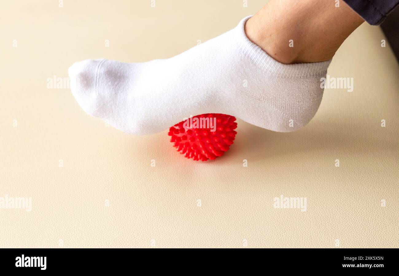 Person, die einen tragbaren Massageball verwendet und den Fuß massiert Stockfoto