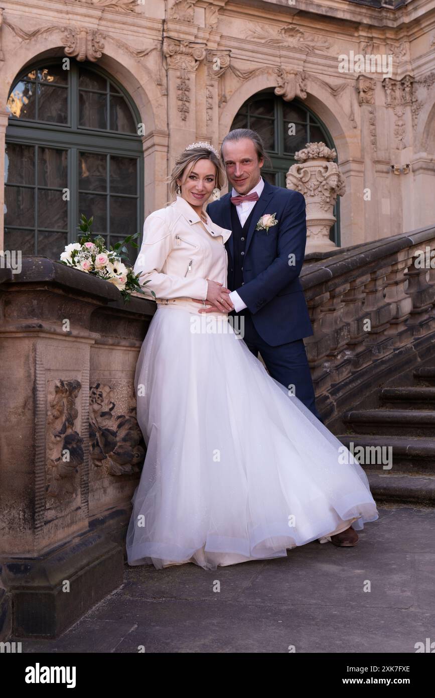 Wunderschönes Paar an ihrem Hochzeitstag. Foto der Braut und des Bräutigams in voller Länge. Ein verliebtes Paar steht auf den Steinstufen des Palastes Stockfoto